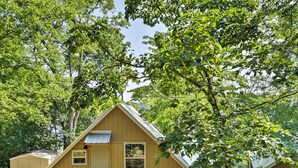 Une petite cabane à un seul étage, dotée d’un toit en pente, d’un porche à l’avant et d’une petite terrasse.