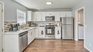 A modern kitchen with white cabinets, stainless steel appliances, and a tiled backsplash. - Spacious + Sunny Austin Home ~ 12 Mi to Dtwn! (Austin)