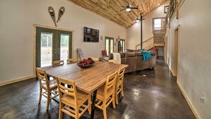 Un'ampia sala da pranzo con tavolo e sedie in legno, un divano e una scala che conduce a un piano superiore.