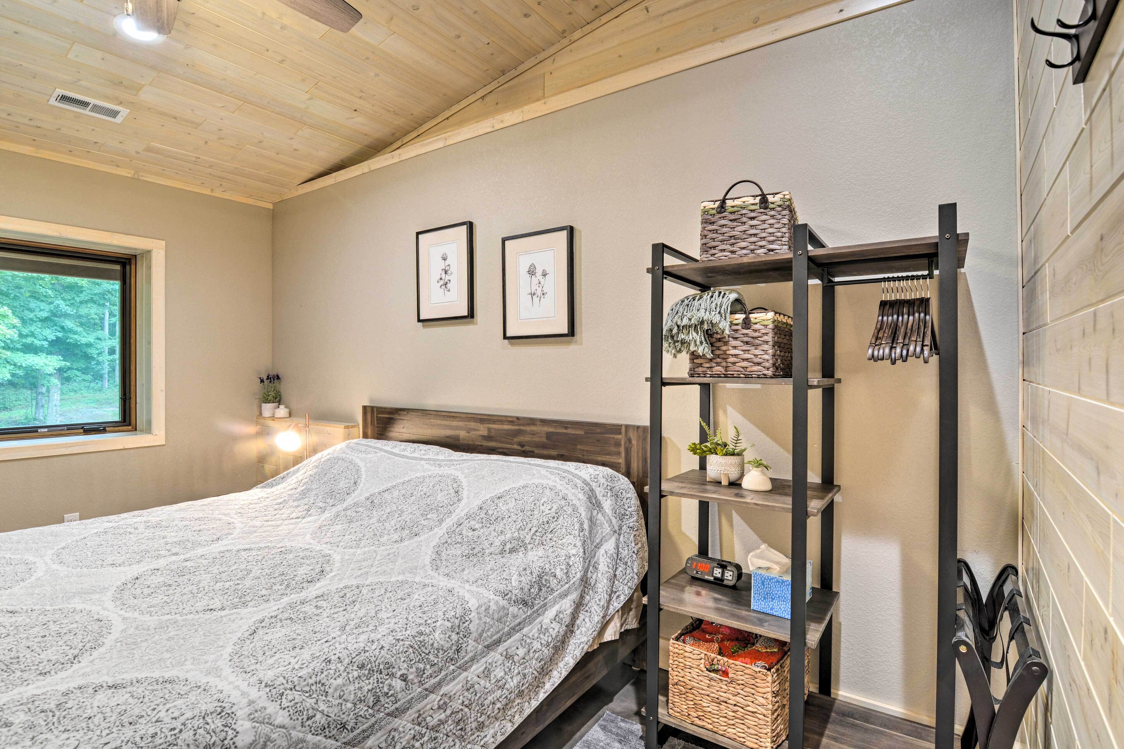 Ein Schlafzimmer mit einem Bett, einem Regal mit Körben, gerahmten Bildern und einem Fenster.