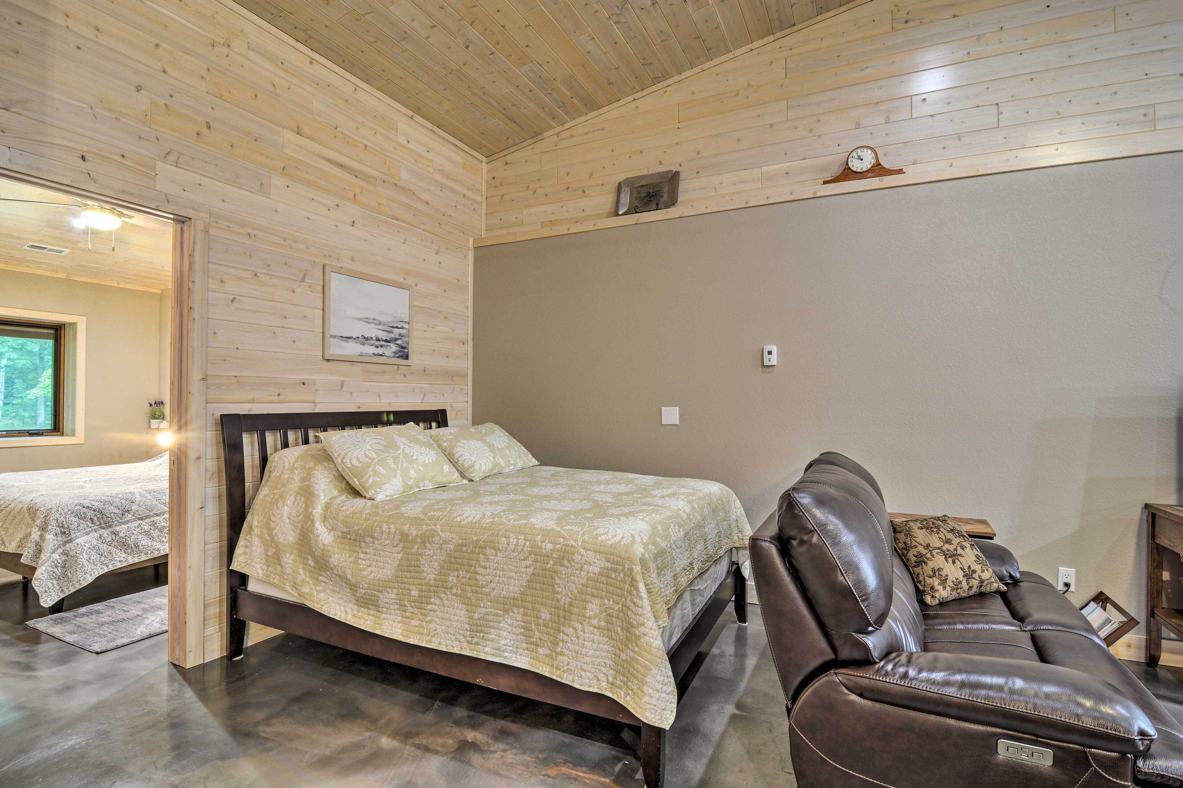 A bedroom with a bed, a reclining chair, and a small table.