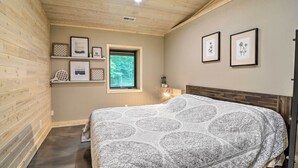 Ein Schlafzimmer mit einem Bett, Holzwänden, einem Fenster und gerahmten Bildern an der Wand.