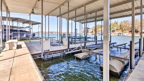 A covered dock with seating and a boat ramp. - Private Boat Dock: Bright Lake Ozark Home! (Lake Ozark)
