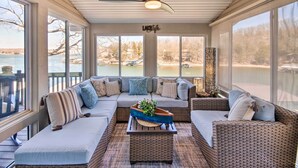 A covered outdoor seating area with a large sectional sofa, a coffee table, and a ceiling fan. - Private Boat Dock: Bright Lake Ozark Home! (Lake Ozark)