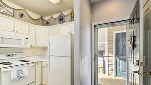 A kitchen with white cabinets, a microwave, a stove, and a refrigerator. - Sunset Beach Resort Condo in Golf Community! (Sunset Beach)
