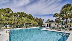 A clear blue pool surrounded by lounge chairs and palm trees, with a building in the background. - Sunset Beach Resort Condo in Golf Community! (Sunset Beach)