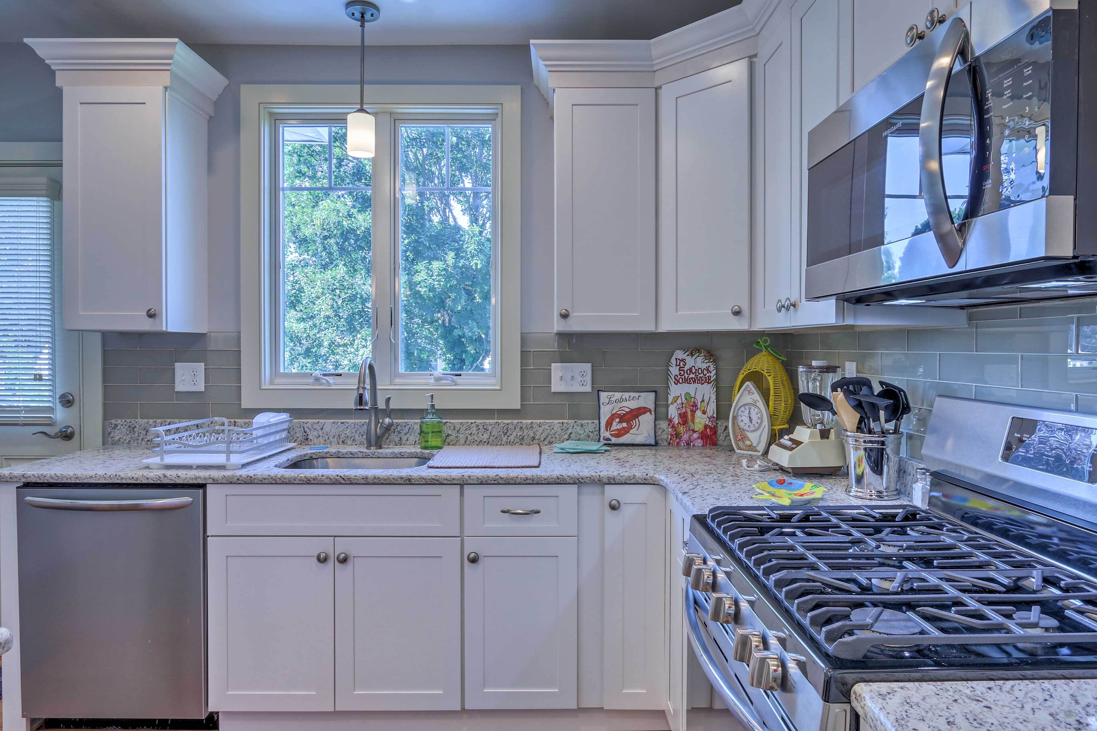 A kitchen with white cabinets, a stainless steel dishwasher, a gas stove, and a microwave.