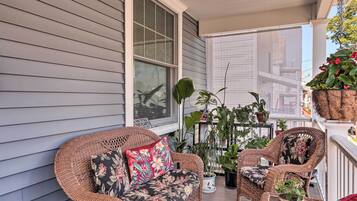 A balcony with wicker furniture, potted plants, and a view of the city.