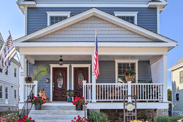 A two-story house with a front porch, a flag, and potted plants. - New London Hideaway Near Beaches & Local Spots! (New London)