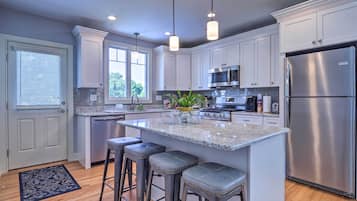 A modern kitchen with white cabinets, stainless steel appliances, and a central island with bar stools.