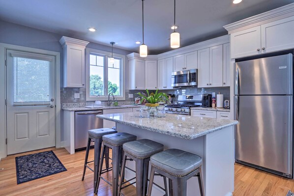 A modern kitchen with white cabinets, stainless steel appliances, and a central island with bar stools.