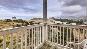 Un balcón con vistas a un paisaje costero, incluyendo dunas y un edificio distante.