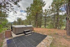 A hot tub set up outdoors with a stone platform and a metal grate, surrounded by trees. - Homey Mtn View Escape: 11 Mi to Garden of the Gods (Cascade)