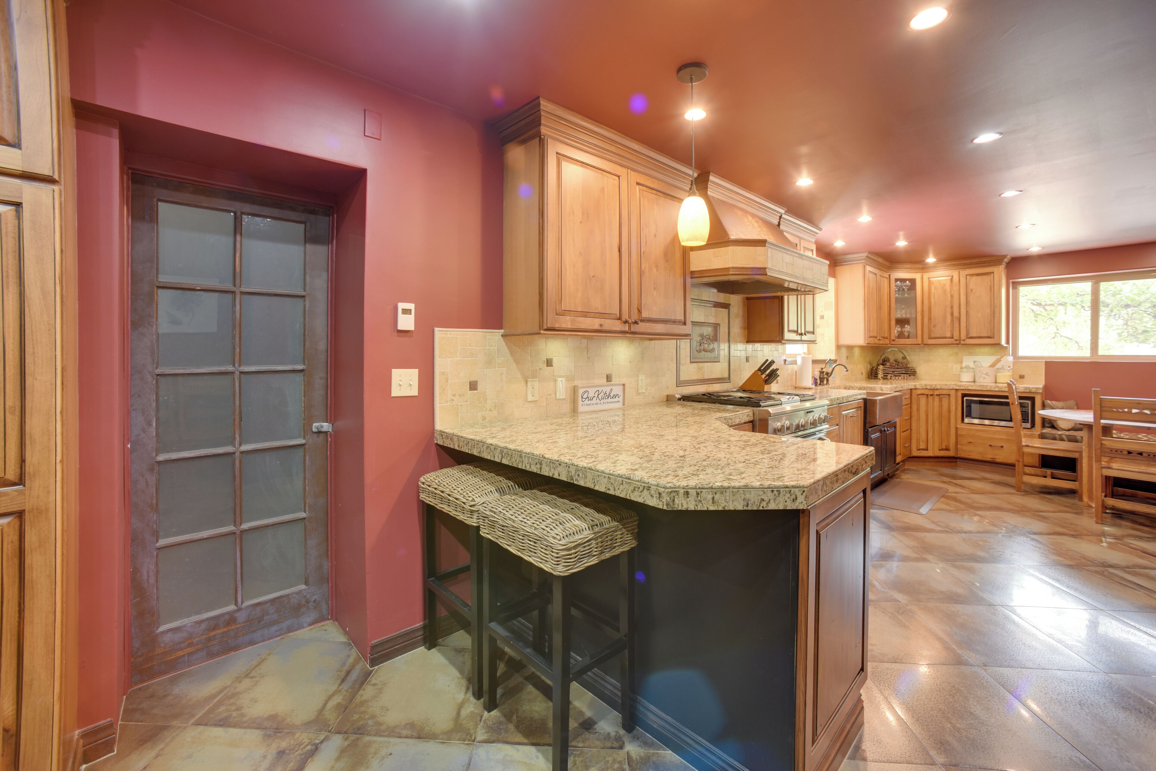 A kitchen with wooden cabinets, a granite countertop, and a bar stool.