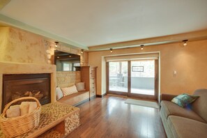 A living room with a fireplace, a sofa, a wicker basket, and a sliding glass door leading to an outdoor patio. - Homey Mtn View Escape: 11 Mi to Garden of the Gods (Cascade)