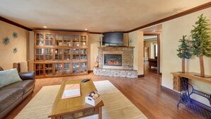 A living room with a stone fireplace, wooden bookshelves, a leather sofa, and a coffee table. - Homey Mtn View Escape: 11 Mi to Garden of the Gods (Cascade)
