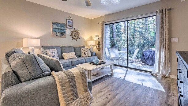A living room with a grey sofa, a coffee table, and a ceiling fan. There is a sliding glass door leading to an outdoor area with a covered table and chairs. - Renovated Gem w/ Pool Access: 1/4 Mi to Beach (Santa Rosa Beach)