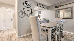 A dining area with a table and chairs, a bicycle mounted on the wall, and a sign that reads "THIS IS OUR HAPPY PLACE". - Renovated Gem w/ Pool Access: 1/4 Mi to Beach (Santa Rosa Beach)