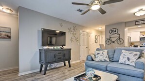 A living room with a grey sofa, a coffee table, a TV, and a ceiling fan. - Renovated Gem w/ Pool Access: 1/4 Mi to Beach (Santa Rosa Beach)