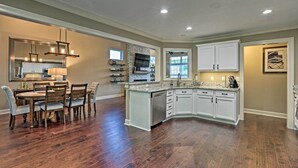 A spacious kitchen with a central island, white cabinetry, and a dining area with a wooden table and chairs. - Spacious Family Home w/ Fire Pits, Large Yard (Goshen)