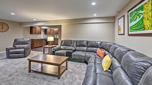 A modern living room with a sectional sofa, a leather armchair, and a wooden coffee table. - Spacious Family Home w/ Fire Pits, Large Yard (Goshen)