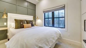 Ein Schlafzimmer mit einem großen Bett, einem Fenster mit Jalousien und zwei Nachttischlampen.