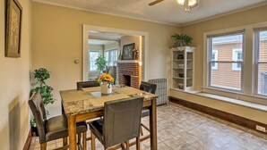 Un comedor con mesa y sillas de madera, ventilador de techo y chimenea de ladrillo.