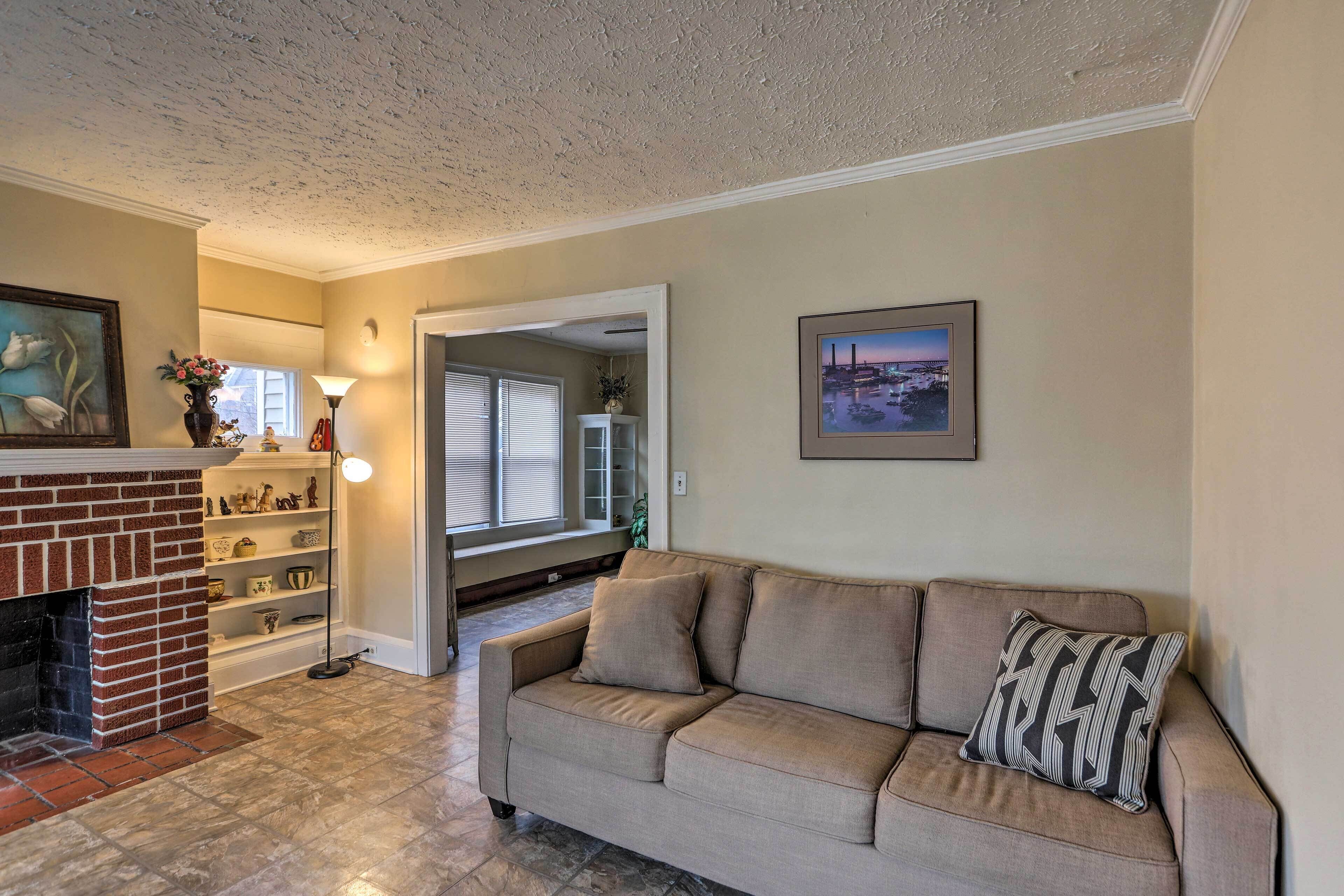 A living room with a beige sofa, a fireplace, a floor lamp, and a bookshelf.