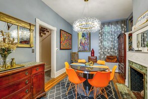 A dining area with a round table, orange chairs, a chandelier, and a fireplace. - Celebrate Dc250! Historic, Walkable Georgetown Gem (Washington)