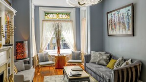 Un salon avec une cheminée, un canapé, une table basse et une grande fenêtre avec des rideaux.