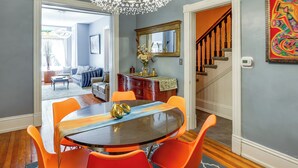 Un coin repas avec une table ronde, des chaises orange et un lustre.