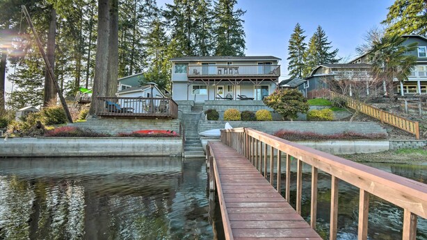 Une propriété située au bord de l’eau, dotée d’une terrasse en bois qui mène à une maison avec balcon.
