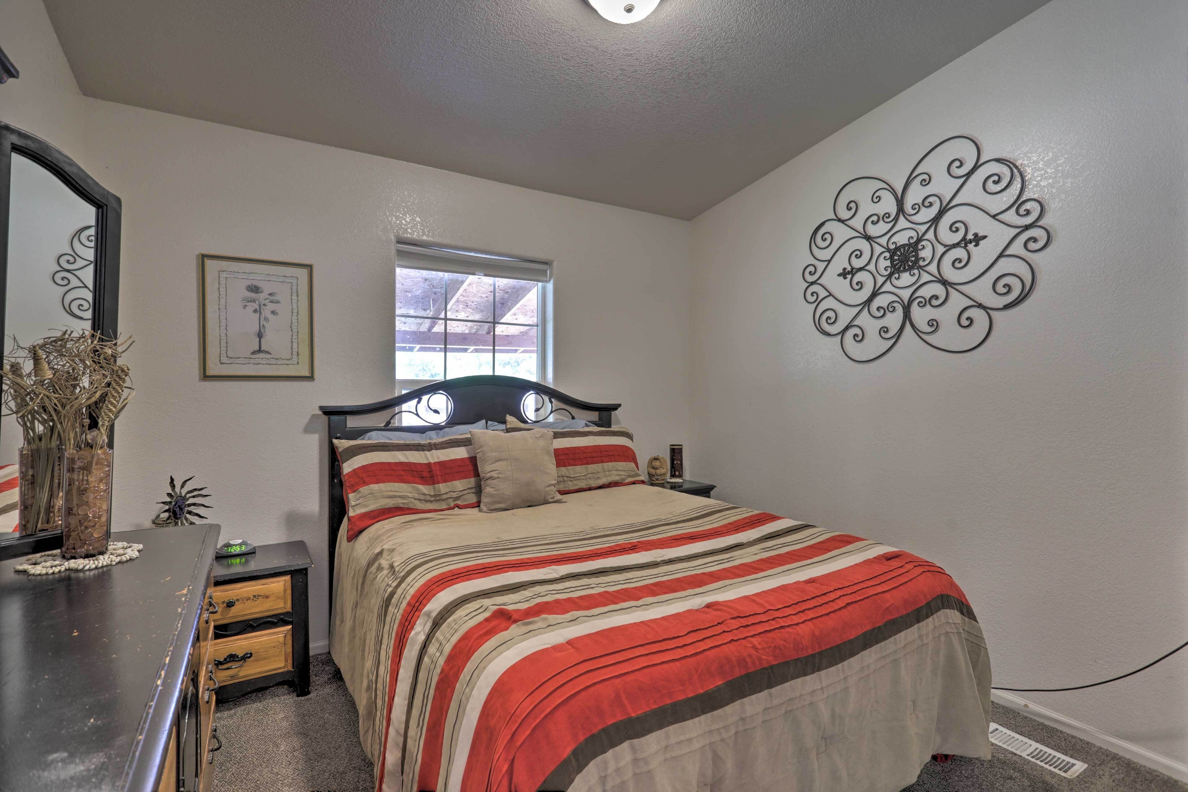 A bedroom with a bed, dresser, window, and wall decor.