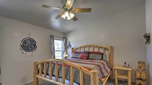A bedroom with a wooden bed, a small wooden nightstand, a ceiling fan, a window, and a wall decoration. - 'rustic Retreat' Moab Townhome w/ Grill & Fire Pit (Moab)