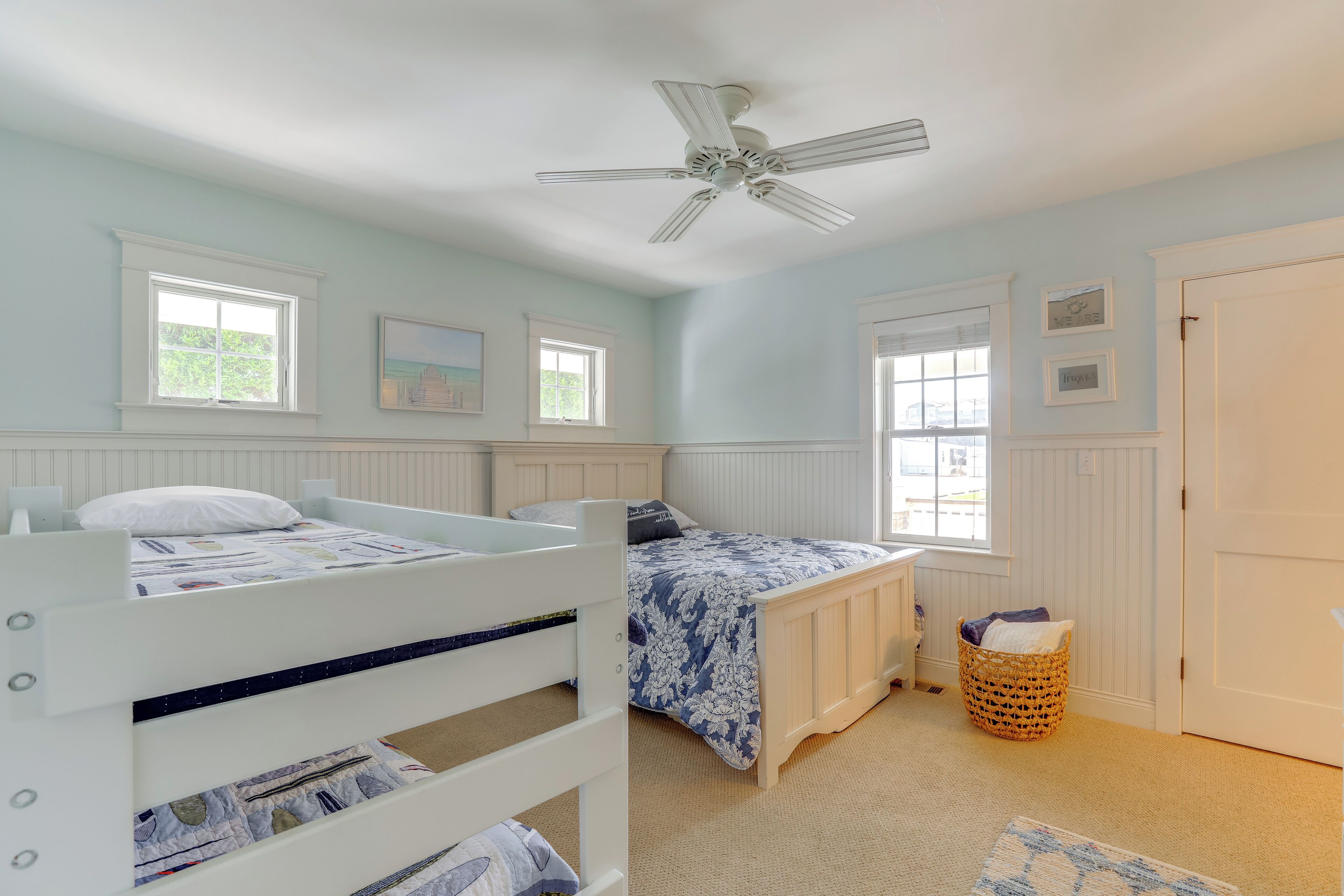 Une chambre avec un lit superposé, un lit simple, un ventilateur de plafond et une fenêtre donnant sur un beau paysage.