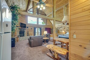 A log cabin interior with a fireplace, a sofa, a dining table, and a ceiling fan. - Gatlinburg Cabin w/ Mtn-view Deck ~ 11 Mi to Dtwn (Gatlinburg)