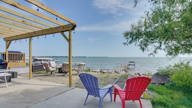 A wooden pergola with string lights, a grill, and outdoor seating by a lake. - Lakefront Retreat w/ Fire Pit & Dock in Castlewood (Castlewood)
