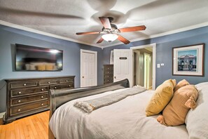 Ein Schlafzimmer mit einem Bett, einem Deckenventilator, einer Kommode und einem gerahmten Bild an der Wand.