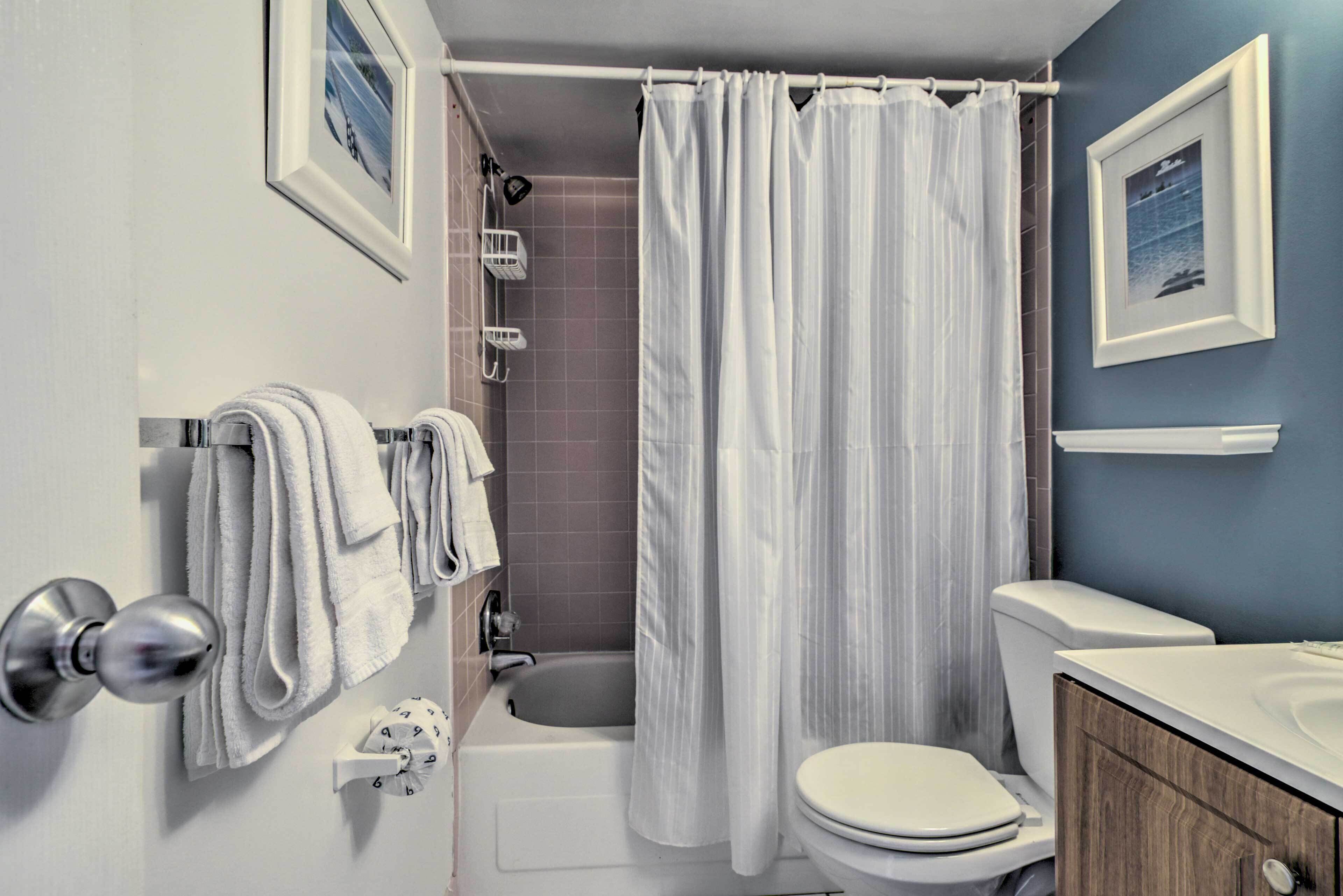 A bathroom with a bathtub, toilet, and a shower curtain.