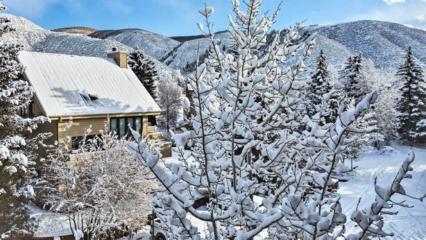 A house with a sloped roof, surrounded by snow-covered trees and mountains in the background. - Colorado Escape w/ Pool Access & Mountain Views! (Avon)