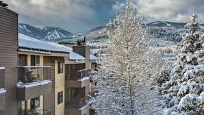 A multi-story building with balconies, a view of snow-covered mountains, and a tree in the foreground. - Colorado Escape w/ Pool Access & Mountain Views! (Avon)