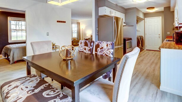 Una cocina moderna con una isla central, electrodomésticos integrados y un comedor con mesa de madera y sillas estampadas.