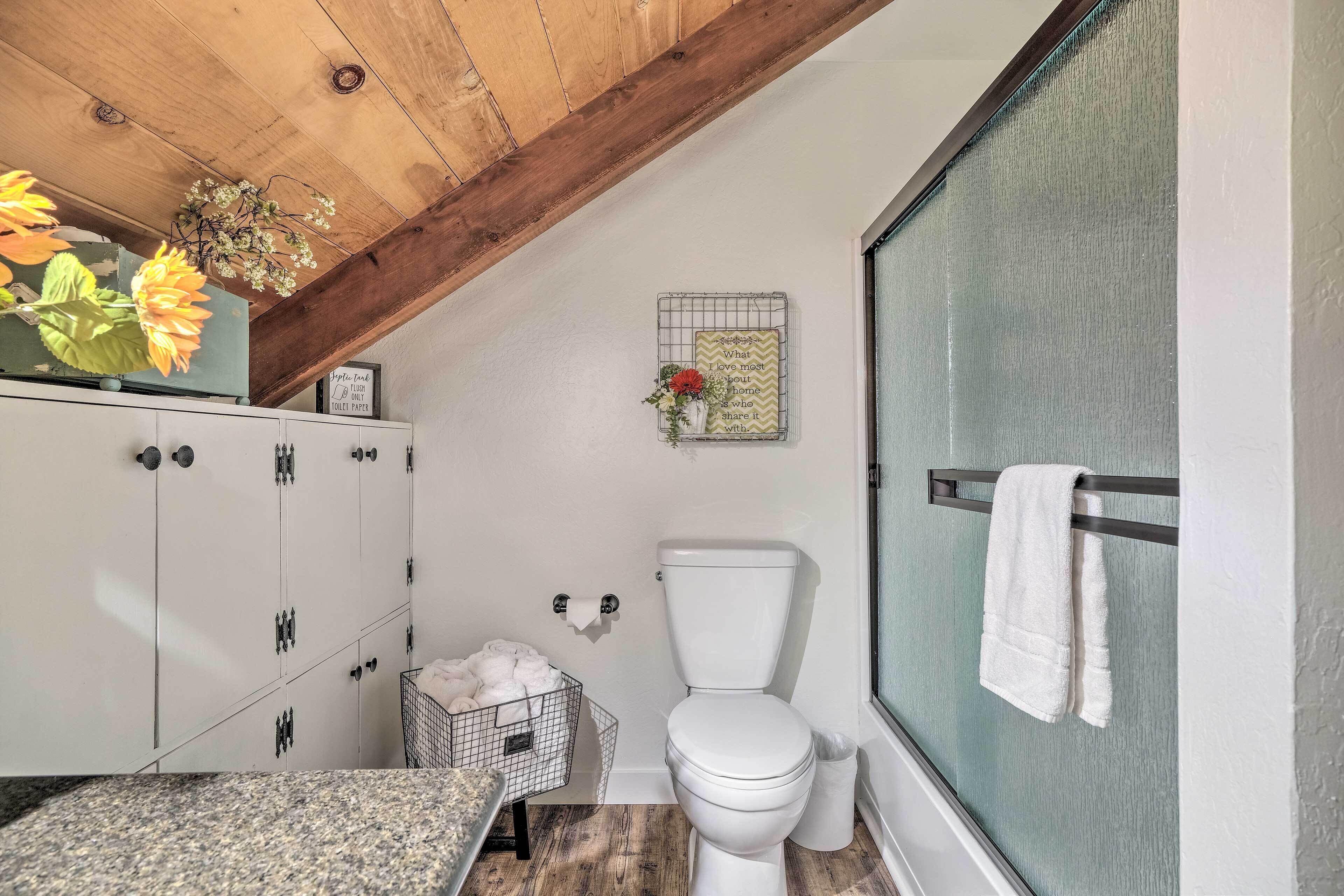 Une salle de bain équipée de toilettes, d’un porte-serviettes, d’un rideau de douche et d’un meuble de rangement.