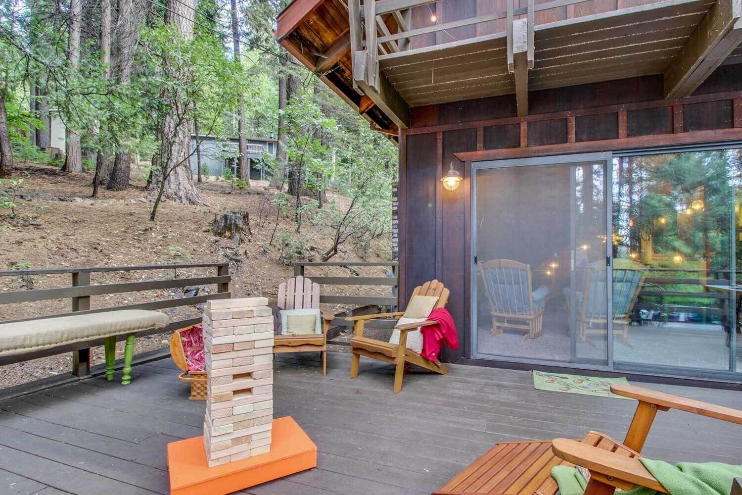 Un terrazzo in legno con posti a sedere all'aperto, una pila di mattoni e una porta in vetro che dà su una zona coperta.