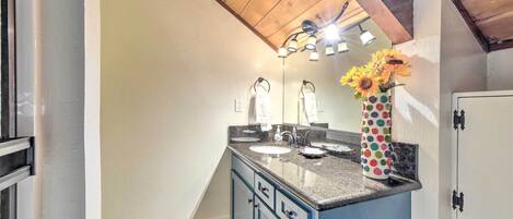 A bathroom with a wooden ceiling, a sink with a mirror, and a vase with sunflowers.