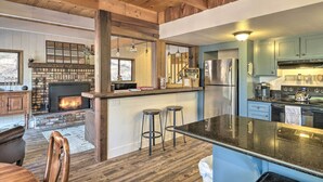 A kitchen with a central island, bar stools, a fireplace, and a stainless steel refrigerator.