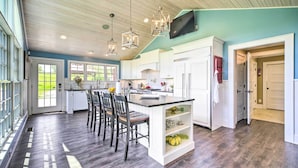 Un'ampia cucina con una grande isola, mobili bianchi e soffitto in legno.