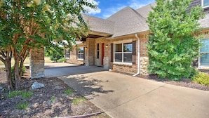 A two-story house with a brick exterior, a front porch, and a driveway leading to the entrance. - Spacious Stallion Lake Ranch Home w/ Patio (Lindale)