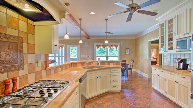 A kitchen with a gas stove, white cabinets, a ceiling fan, and a large window. - Spacious Stallion Lake Ranch Home w/ Patio (Lindale)