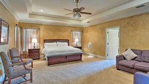 A spacious bedroom with a large bed, a sitting area with a couch, and a ceiling fan. - Spacious Stallion Lake Ranch Home w/ Patio (Lindale)